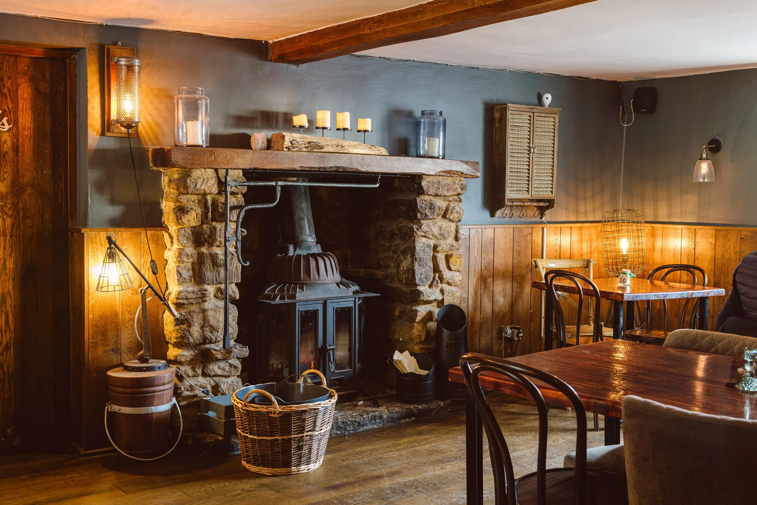 The warm interior of The Copper Kettle pub with oak beams and an open fire